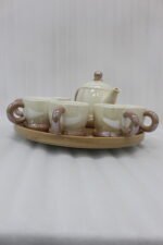 Beige and brown ceramic tea set with 6 cups, a teapot, and a rotating tray arranged on a kitchen counter
