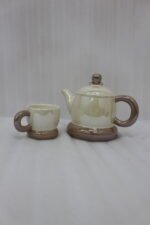 Beige and brown ceramic tea set with 6 cups, a teapot, and a rotating tray arranged on a kitchen counter
