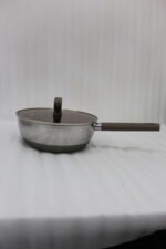 A collection of high-quality titanium stainless steel woks and frying pans in sizes 24cm, 26cm, 28cm, and 30cm with glass lids and ergonomic handles displayed on a kitchen counter.