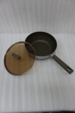 A collection of high-quality titanium stainless steel woks and frying pans in sizes 24cm, 26cm, 28cm, and 30cm with glass lids and ergonomic handles displayed on a kitchen counter.