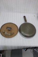 Three sizes of premium non-stick titanium fry pans with matching glass lids and brown ergonomic handles displayed on a granite countertop.