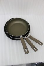 Three sizes of premium non-stick titanium fry pans with matching glass lids and brown ergonomic handles displayed on a granite countertop.