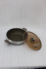 Four stainless steel double-handle woks with glass lids in 24cm, 26cm, 28cm, and 30cm sizes displayed on a dark kitchen countertop.