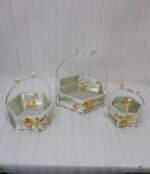 Three hexagonal silver and gold floral decorative serving dishes with handles resting on a wooden coffee table