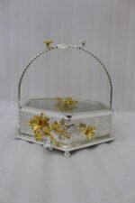 Three hexagonal silver and gold floral decorative serving dishes with handles resting on a wooden coffee table