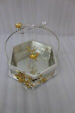 Three hexagonal silver and gold floral decorative serving dishes with handles resting on a wooden coffee table