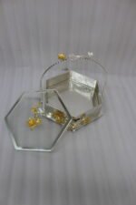Three hexagonal silver and gold floral decorative serving dishes with handles resting on a wooden coffee table