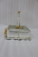 Three silver textured decorative serving dishes with gold floral accents and overhead arched handles on a wooden coffee table.
