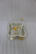 Three-piece silver hammered decorative bowl set with gold floral accents and overhead handles arranged on a wooden table.