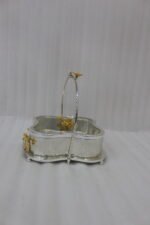 Three-piece silver hammered decorative bowl set with gold floral accents and overhead handles arranged on a wooden table.