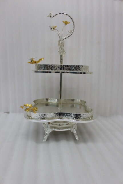 Two-tier silver hammered decorative serving tray with gold floral accents resting on a wooden coffee table in an elegant living room setting.