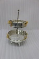 Two-tiered textured silver serving stand with gold floral accents displayed on a wooden table.