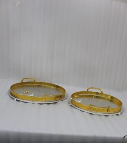 Round hammered metal decorative serving tray with dual gold handles and detailed silver and gold floral branch accent on a kitchen countertop.