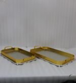 Set of two luxury gold and silver rectangular decorative serving trays with Greek key pattern borders resting on a white marble countertop.