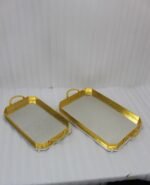 Set of two luxury gold and silver rectangular decorative serving trays with Greek key pattern borders resting on a white marble countertop.