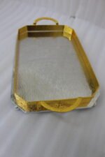 Set of two luxury gold and silver rectangular decorative serving trays with Greek key pattern borders resting on a white marble countertop.