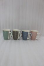 4-piece ceramic coffee mug set with gold star patterns in sage green, brown, navy blue, and blush pink on a white marble countertop.