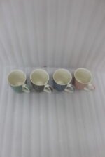 4-piece ceramic coffee mug set with gold star patterns in sage green, brown, navy blue, and blush pink on a white marble countertop.