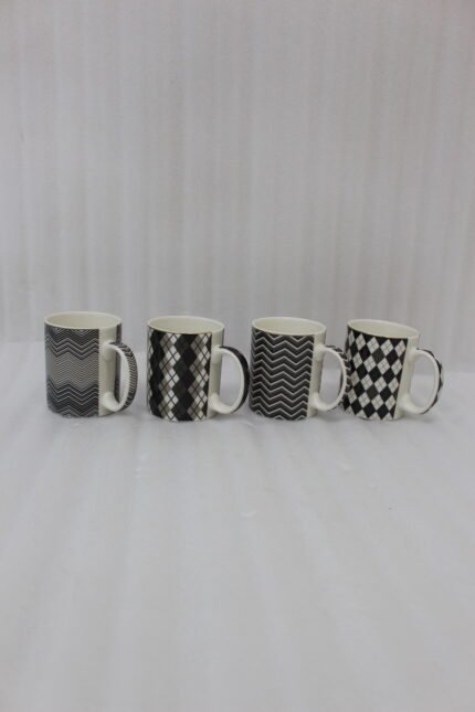 Four-piece modern black and white ceramic coffee mug set with geometric chevron and argyle patterns lined up on a kitchen counter.