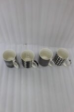 Four-piece modern black and white ceramic coffee mug set with geometric chevron and argyle patterns lined up on a kitchen counter.