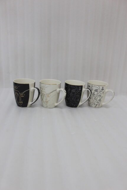 Set of 4 OneMore ceramic coffee mugs featuring abstract face line art in black, white, and gold on a kitchen countertop.