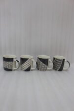 Set of 4 modern ceramic coffee mugs with distinct black, white, and grey geometric patterns displayed on a kitchen countertop.