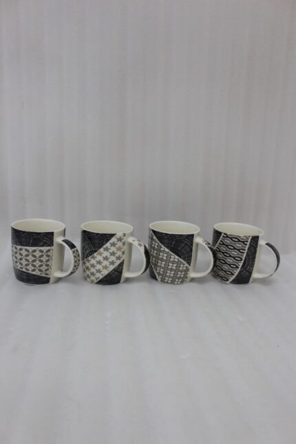 Set of 4 modern ceramic coffee mugs with distinct black, white, and grey geometric patterns displayed on a kitchen countertop.