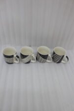 Set of 4 modern ceramic coffee mugs with distinct black, white, and grey geometric patterns displayed on a kitchen countertop.