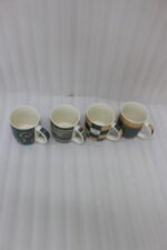 A row of four modern ceramic coffee mugs with black, cream, and brown coffee house patterns lined up on a white kitchen countertop.