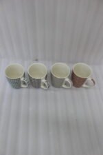 Set of four ceramic coffee mugs with unique geometric patterns in blue, grey, charcoal, and terracotta displayed on a kitchen counter.