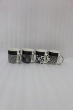 Set of four modern ceramic coffee mugs featuring black and white geometric patterns lined up on a granite countertop.