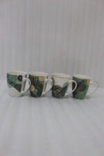 Four white ceramic coffee mugs lined up on a marble countertop with green, gold, and black abstract tribal patterns and comfortable handles.