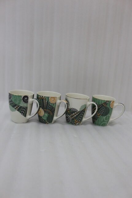 Four white ceramic coffee mugs lined up on a marble countertop with green, gold, and black abstract tribal patterns and comfortable handles.