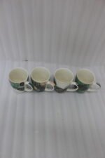 Four white ceramic coffee mugs lined up on a marble countertop with green, gold, and black abstract tribal patterns and comfortable handles.