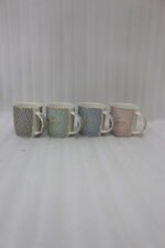 Four ceramic coffee mugs with pastel floral patterns in grey, green, blue, and pink featuring gold rims on a marble kitchen countertop.