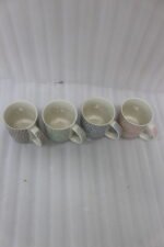 Four ceramic coffee mugs with pastel floral patterns in grey, green, blue, and pink featuring gold rims on a marble kitchen countertop.