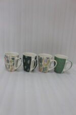 Four ceramic coffee cups featuring green, yellow, and beige geometric and botanical patterns lined up on a granite kitchen countertop