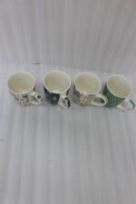 Four ceramic coffee cups featuring green, yellow, and beige geometric and botanical patterns lined up on a granite kitchen countertop