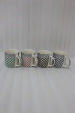 Four ceramic coffee mugs with gingham and polka dot patterns lined up on a marble countertop