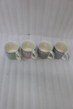 Four ceramic coffee mugs with gingham and polka dot patterns lined up on a marble countertop