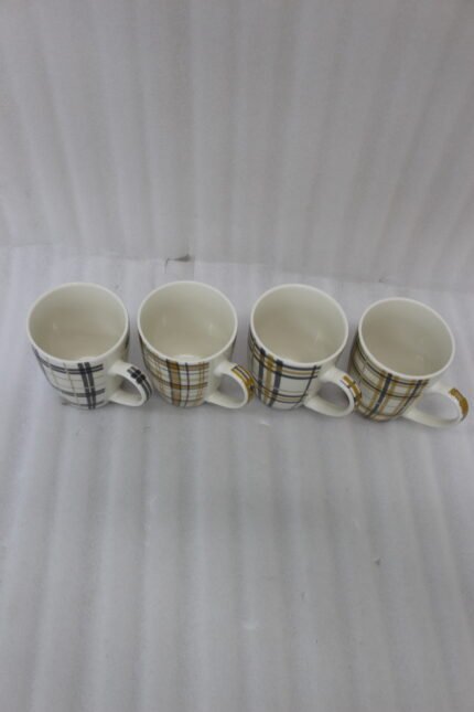 Set of four modern plaid ceramic coffee mugs displayed on a white marble kitchen countertop.