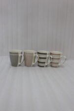 Four ceramic coffee cups with vertical and horizontal striped patterns lined up on a kitchen counter