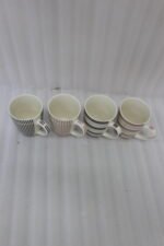 Four ceramic coffee cups with vertical and horizontal striped patterns lined up on a kitchen counter