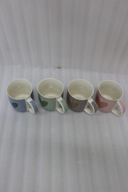 Four ceramic coffee mugs lined up on a kitchen counter in blue, green, brown, and pink with textured dot patterns and gold heart details.