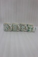 Four Onemore ceramic coffee mugs with teal and grey geometric patterns arranged on a wooden kitchen countertop.