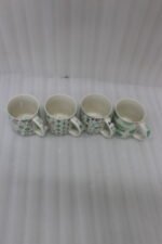 Four Onemore ceramic coffee mugs with teal and grey geometric patterns arranged on a wooden kitchen countertop.