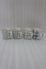 Set of 4 ceramic coffee mugs with blue and grey plaid grid patterns displayed on a kitchen countertop.