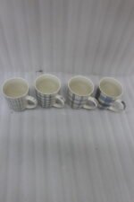 Set of 4 ceramic coffee mugs with blue and grey plaid grid patterns displayed on a kitchen countertop.