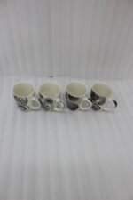 Set of 4 cream ceramic coffee mugs with distinct black geometric and swirl patterns displayed on a white marble countertop