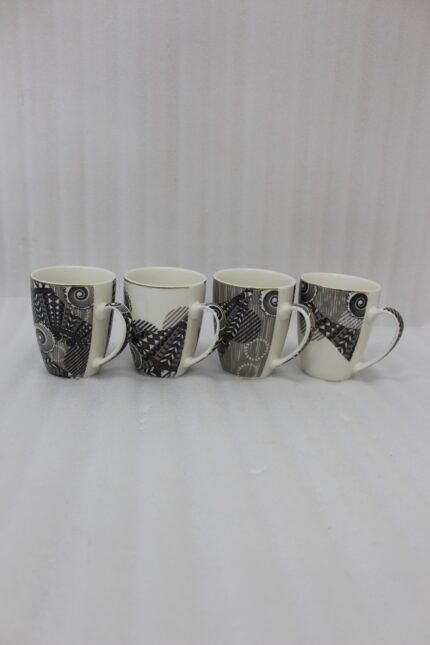 Set of 4 white ceramic coffee mugs featuring modern black geometric patterns lined up on a kitchen countertop.